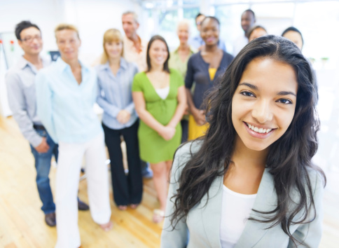 Beautiful young woman with colleagues in the background.