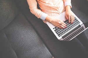 A woman sitting on a couch using a laptop.