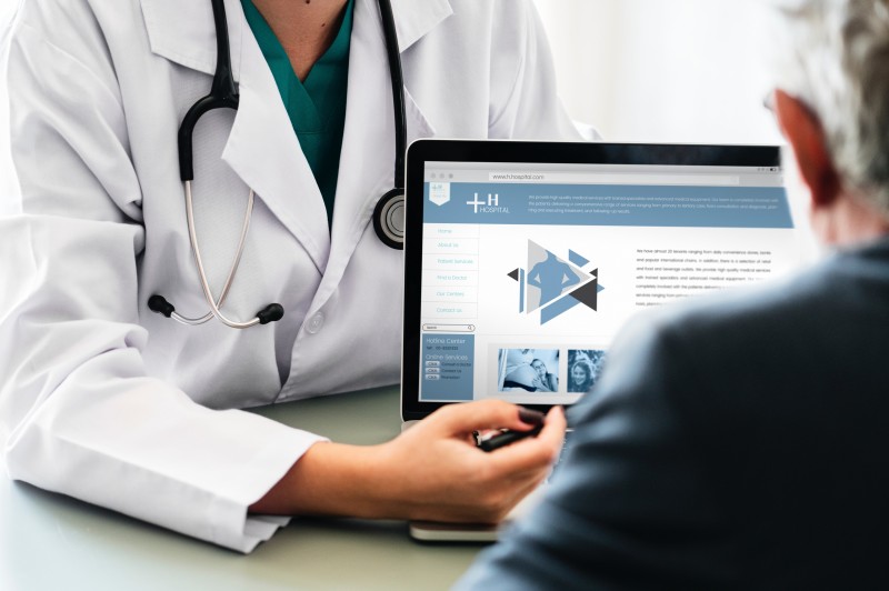 a doctor showing data in the laptop's website to the patient