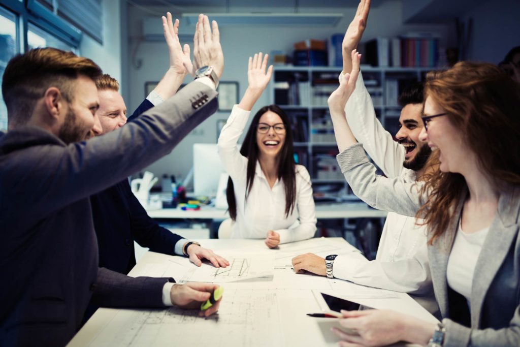 A group of business people raising their hands in the air.