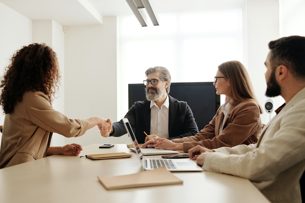 A group of new business partners shaking hands at a conference table.